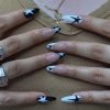 Two hands presenting a set of almond-shaped press-on nails, featuring a stunning mix of black and light pink, adorned with star art.