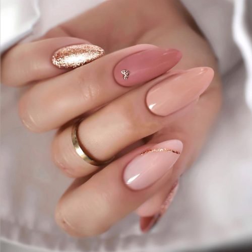 Hand wearing five gold glitter press on nails, nails French tip, almond nails.