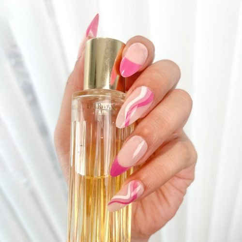 Hand with light pink and purple-red press-on nails, designed nails French tip, holding a perfume bottle, almond nails.