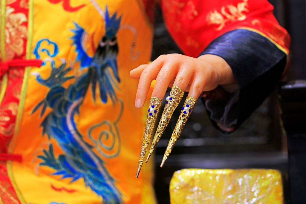 Hand with elongated nails of a woman adorned in traditional Ming Dynasty attire.