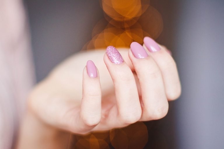 A hand wearing pink press-on nails.