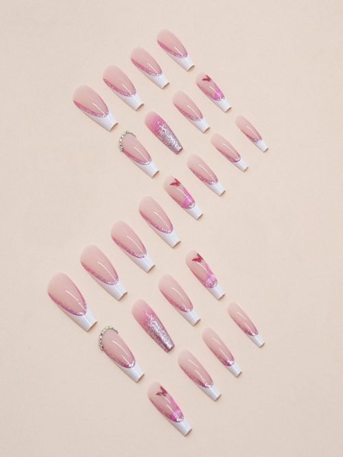 Top-down view of a set of long coffin-shaped press-on nails in pink shade with white French glitter tips, diamonds, and butterfly accessories.