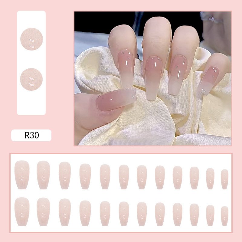 Top-down view of a 24-piece set of long coffin-shaped artificial nails in various sizes, featuring a nude shade with white French tips.