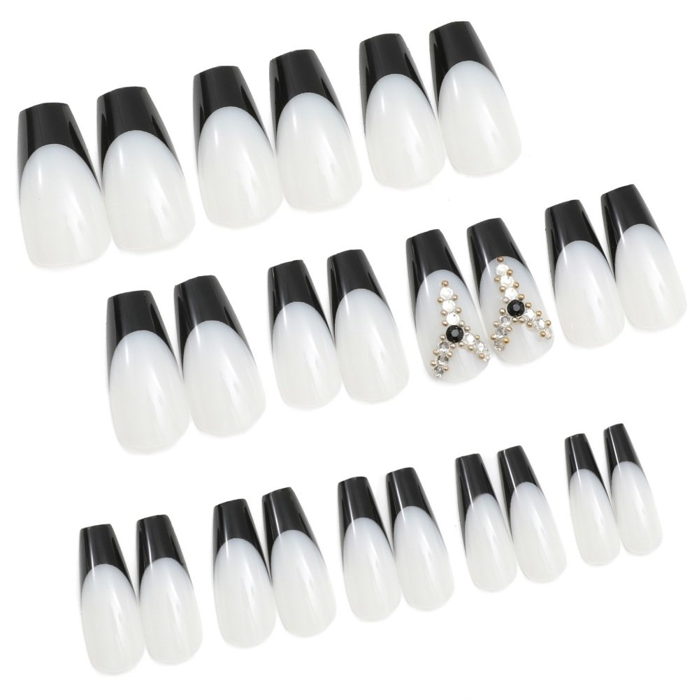 Set of 24 coffin press-on nails in white with black French tips; two nails adorned with diamond embellishments.