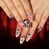 Hands showcasing a set of almond press-on nails with Halloween-themed designs.