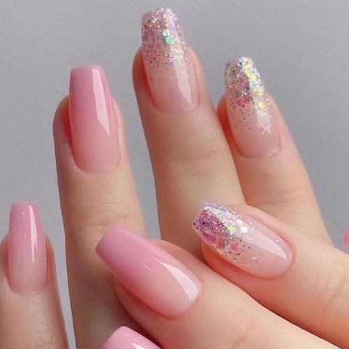 Hands showcasing coffin press-on nails in designs of ombre pink and glitter dip.