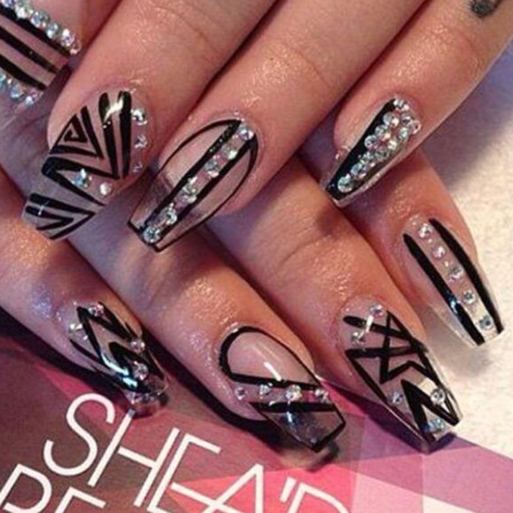 Hands displaying coffin press-on nails in a transparent design with black stripes, adorned with colored diamond accessories.