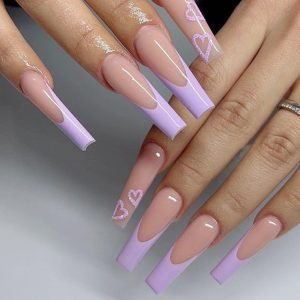 Hands showcasing long coffin press-on nails, some in nude with purple French tips and others in nude with a glitter-dipped heart design.